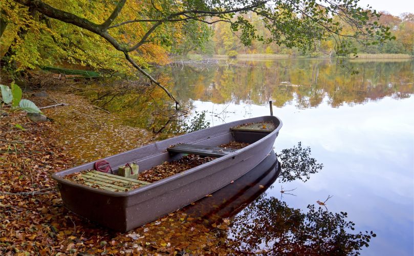 Herbstlandschaft mit See und kleinem Ruderboot